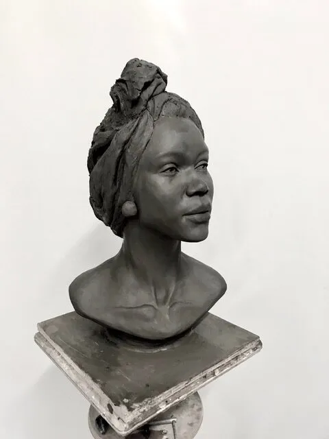 Portrait bust of a woman wearing a headwrap, in clay