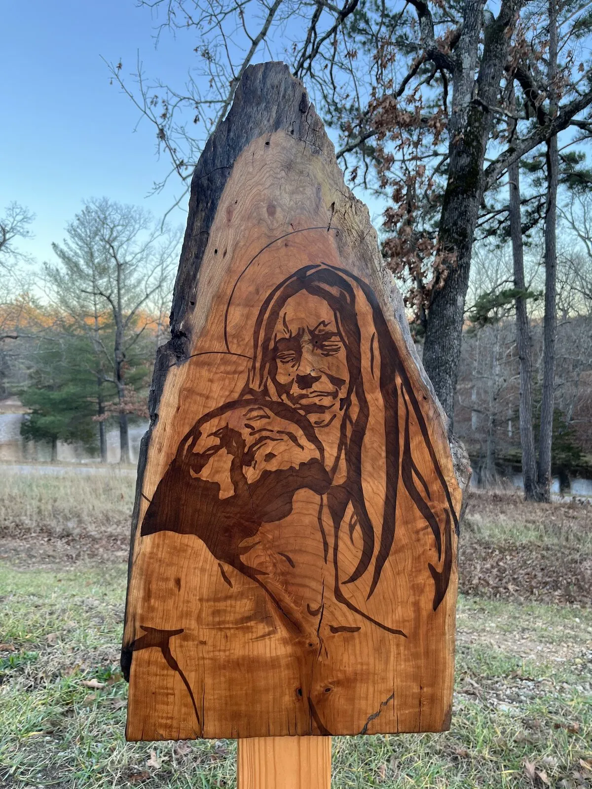 Mary holding the body of Jesus, stained into a wood panel, photographed at sunset