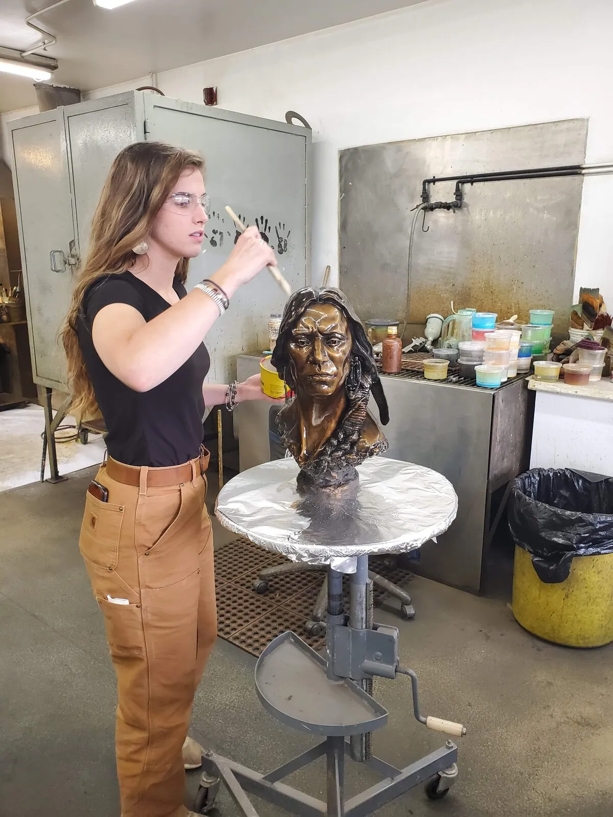 Riley Root patinating a bronze portrait bust in the studio